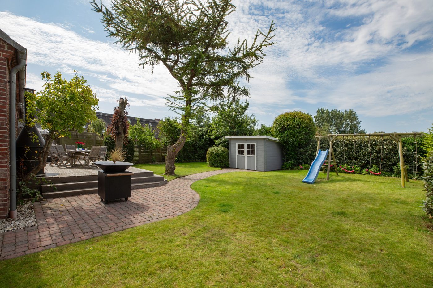 Eingezäunter Garten mit Rasen, Rutsche, Gartenhaus und Terrasse